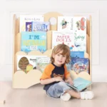 Boy sitting beside the bookshelf showing front-facing book covers
