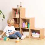 Child playing on the floor beside the stepped modular storage cubes