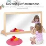 Toddler discovering their own reflection in the full-length safety mirror