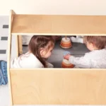 Two toddlers playing inside the mirrored playhouse den