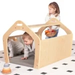 Children playing around the wooden playhouse on a patterned rug