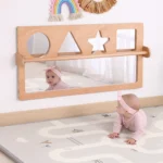Baby using the mirror set on the floor for tummy time and crawling practice