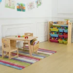 Natural wooden kids table and chairs set in a playroom on a colourful rug