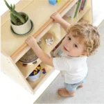Toddler holding the handrail of the bookcase while standing