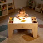 Child stacking translucent blocks on the lit sensory table