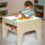 Child sorting translucent shapes on the lit sensory table