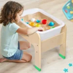 Toddler scooping and pouring at the sand and water table