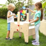 Two children playing at the water and sand table in a garden